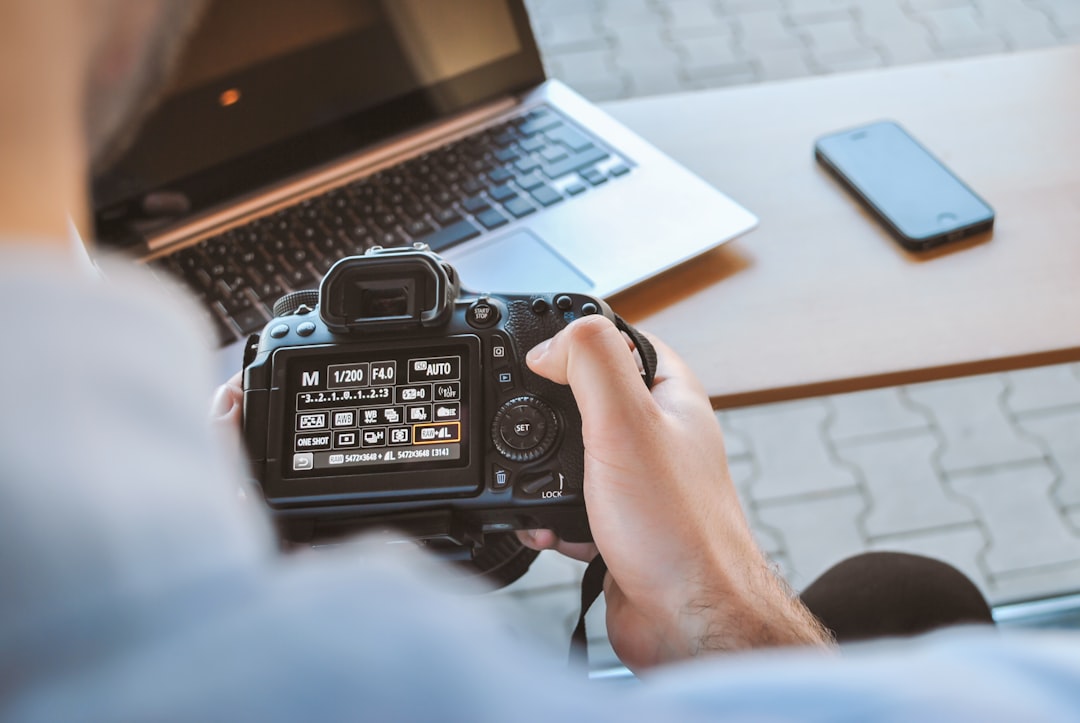 Photo by JESHOOTS.COM person holding black DSLR camera