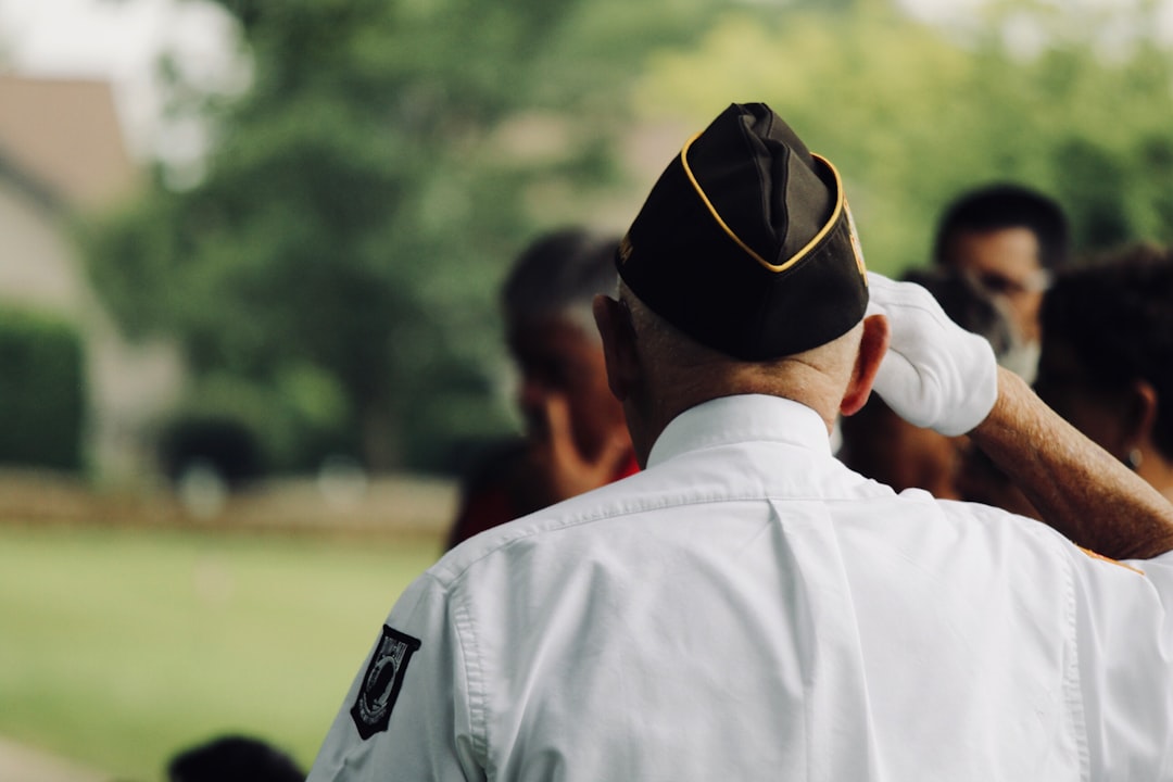 Photo by sydney Rae man wearing white uniform saluting
