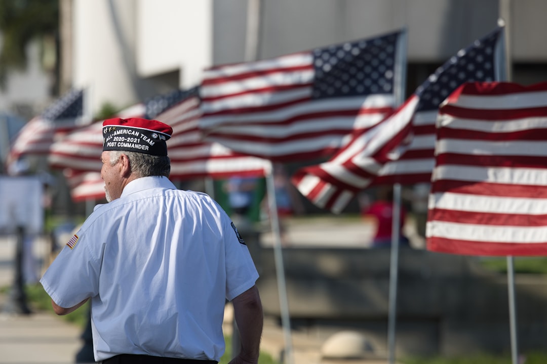 Photo by David Valentine a man standing in front of a row of american flags