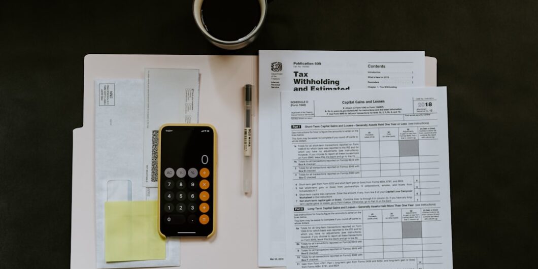 Photo by Kelly Sikkema black Android smartphone near ballpoint pen, tax withholding certificate on top of white folder