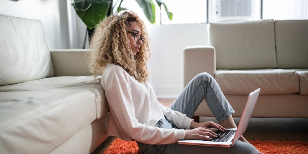 Photo by Thought Catalog woman sitting on floor and leaning on couch using laptop