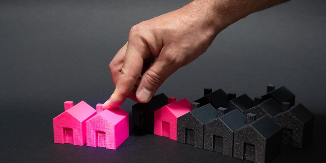A hand is pointing at a small pink house