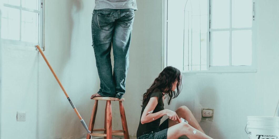 woman in gray tank top and blue denim jeans sitting on bed