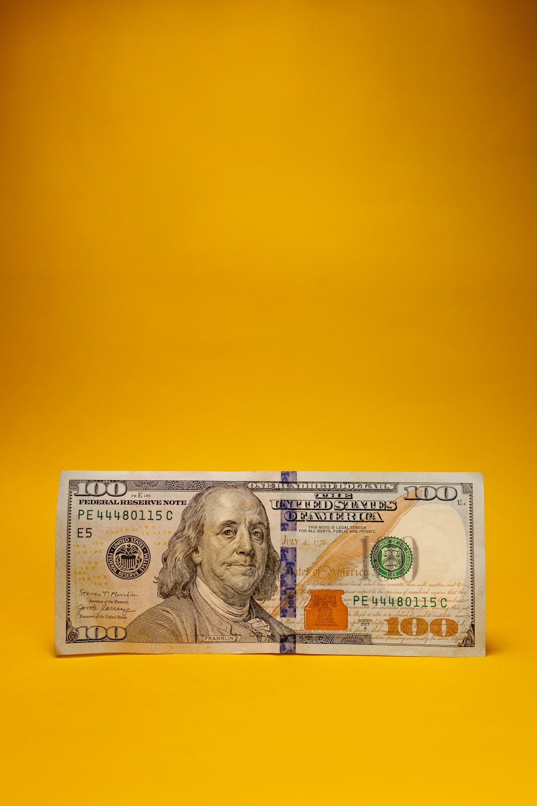 a one hundred dollar bill laying on a yellow background