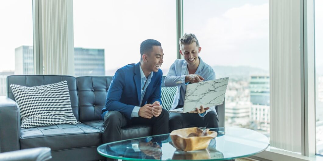 two men in suit sitting on sofa