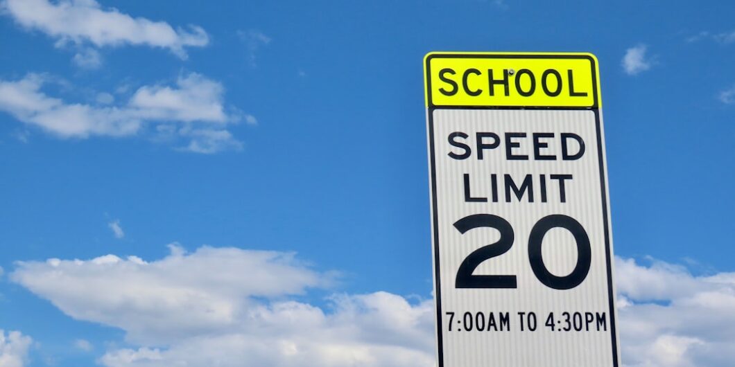 School zone speed limit sign against a cloudy sky.