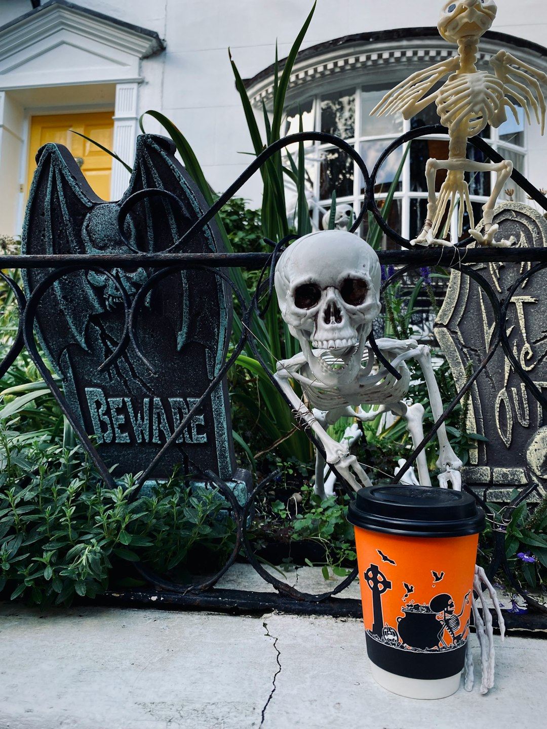 a cup of coffee sitting next to a skeleton statue