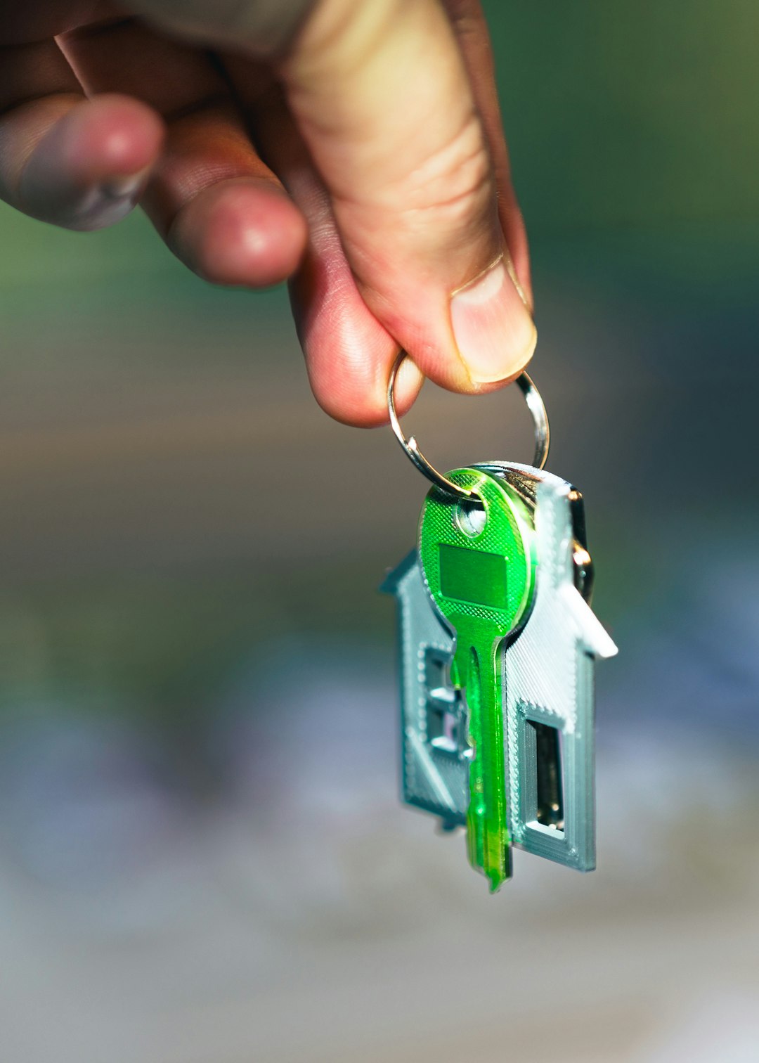 Photo by Jakub Żerdzicki A hand holding a green key to a house