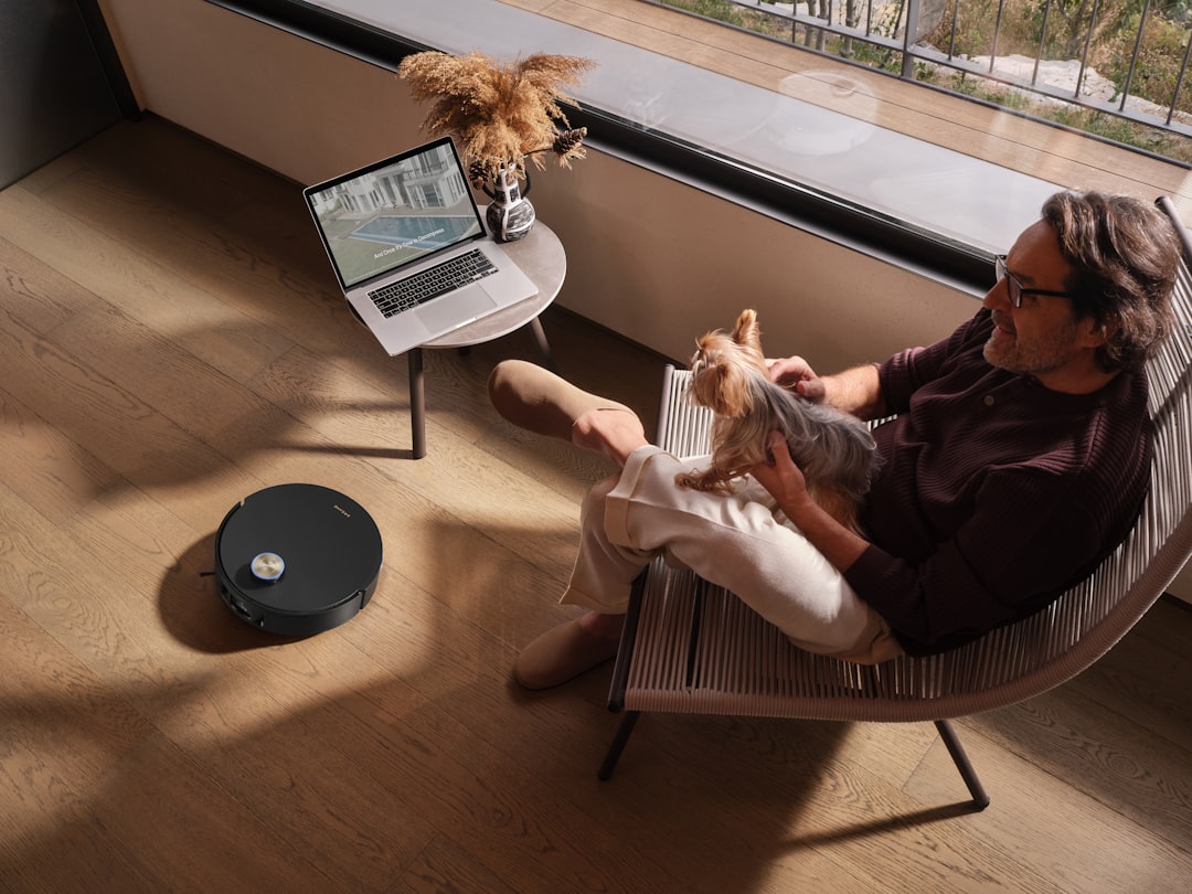 Man relaxing with dog while robot vacuum cleans