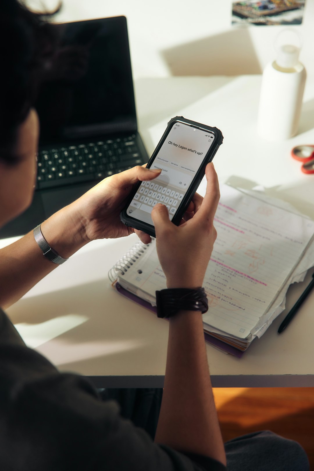Photo by Microsoft Copilot Person using a smartphone over a notebook